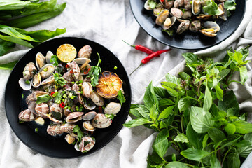 Fresh clams and mussels arranged on plates, garnished with herbs, spices, and citrus.