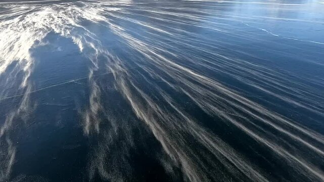 snow drifting in the wind over ice on a frozen lake
