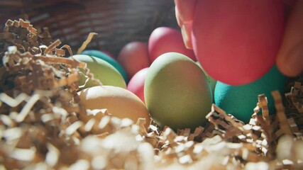 Colorful eggs are being carefully selected from a decorative basket