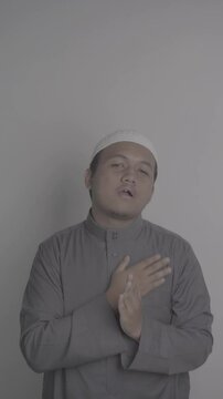 Southeast Asian Muslim man wearing grey robe makes greeting gesture then chats amiably with people around him and video in S-Log3, S-Gamut3.Cine