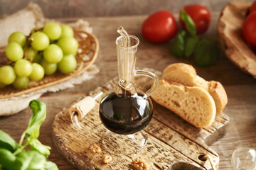A bottle of balsamic vinegar, with ciabatta, fresh basil, grapes and tomatoes