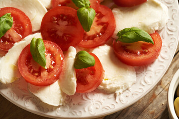 Closeup of Italian Caprese salad - fresh tomatoes, mozzarella cheese and basil leaves