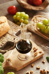 A bottle of balsamic vinegar with tomatoes, ciabatta, grapes and walnuts