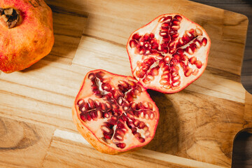 Pomegrenades cut in half on a wooden background.