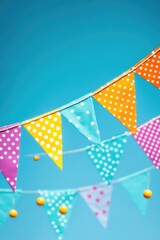 Obraz premium A festive decoration with multicolored polka dots on white flags, against a light blue background.