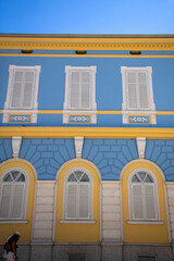 Yellow and blue house. Brightly colored architecture. Windows on the wall. 