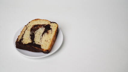 One slice of babka brownie bread served on a white plate with a white background (isolated white).