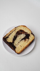 One slice of babka brownie bread served on a white plate with a white background (isolated white).