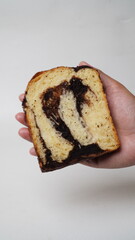 Hand holding a slice of babka brownie bread on a white background (isolated white).