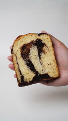 Hand holding a slice of babka brownie bread on a white background (isolated white).