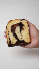 Hand holding a slice of babka brownie bread on a white background (isolated white).