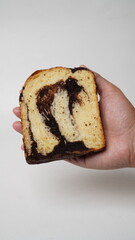 Hand holding a slice of babka brownie bread on a white background (isolated white).