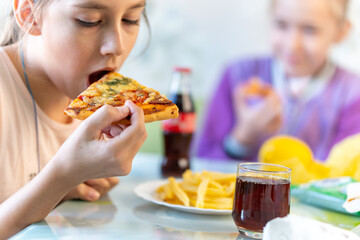 Cute caucasian girl child eating a slice of pizza with cheese, a snack at school, junk food and fast food at children. pizzeria