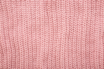 Light pastel pink soft knitted fabric pattern background. Closeup. Top down view.