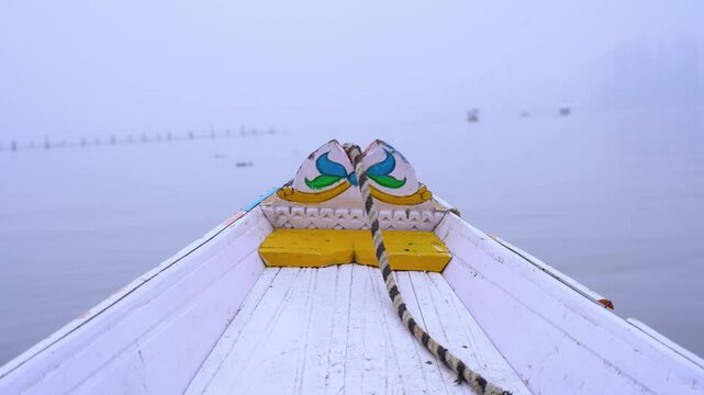 Point of view POV shot of tourist sitting on a gently rocking colorful wooden shikara boat moving into the fog covered dal lake in Srinagar Kashmir