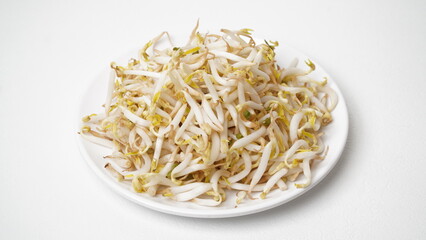 Bean sprouts are served on a white plate and placed on a white surface and background (isolated white).