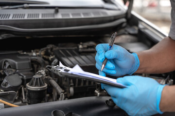 Car mechanic man inspecting and checking list break down car 