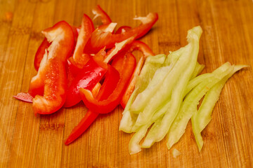 Red and green peppers on a wooden chopping board