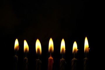 Seven Lit Candles Against a Dark Background Celebrating a Special Occasion