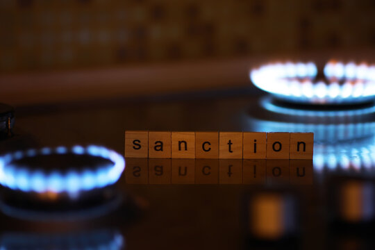 Sanction on Gas Supply: Scrabble Letters Highlighting Energy Crisis with Gas Stove Flames in Background