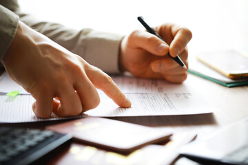 Close-Up of Hands Completing Paperwork with Pen and Calculator on Desk