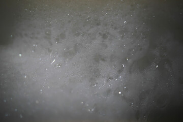 Close-Up of Frothy Soap Bubbles with Shimmering Texture in Dark Lighting