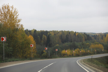 Autumn Road Winding Through Countryside with Forest and Direction Signs