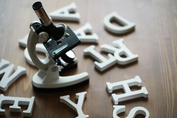 Microscope on Wooden Surface Scattered with Alphabet Letters - Scientific Education Concept