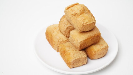 A portion of food called tahu pong is served using a white plate placed on a white place and background (isolated white).