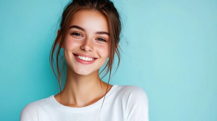 A cheerful young woman flashes a bright smile, her happiness illuminating the space around her. Her carefree attitude enhances the lively turquoise background, creating a vibrant atmosphere