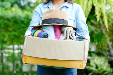 Volunteer collect cloth and hat in cardboard box to donate.