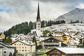 Fototapeta premium Zuoz, Dorf, Oberengadin, Engadiner Dorf, Kirche, San Luzi, Graubünden, Alpen, Inn, Fluss, Engadiner Häuser, Wanderweg, Landwirtschaft, Herbst, Herbstwanderung, Wintereinbruch, Schweiz