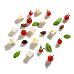 White cheese cubes, cherry tomatoes, basil leaves and olives salad concept ,top view, studio shot