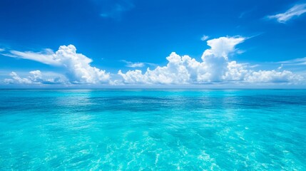 Obraz premium Beautiful, clear blue water and sky background with white clouds on the horizon, a beautiful tropical seascape.