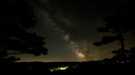 Fototapeta premium Night Sky View of the Milky Way Galaxy Above Dark Silhouette Trees and a Distant Horizon Landscape