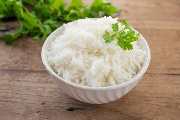 Cooked white rice or steamed rice in a white bowl on wooden background