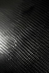 Close-up view of textured black carbon fiber surface showcasing intricate patterns and reflections (1)