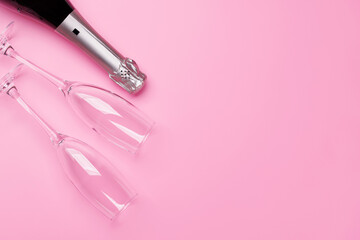 A stylish champagne bottle with elegant glasses on a soft pink background