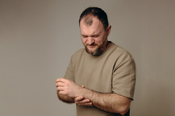 A man holds his wrist in pain. The hand tightly clasps the affected area, emphasizing the soreness...