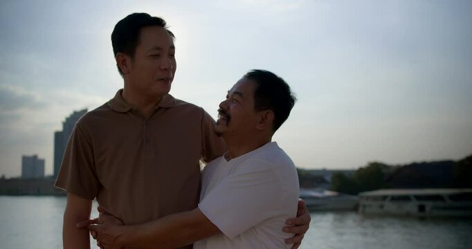Two men enjoying a sunset by the river and embracing each other in a moment of connection