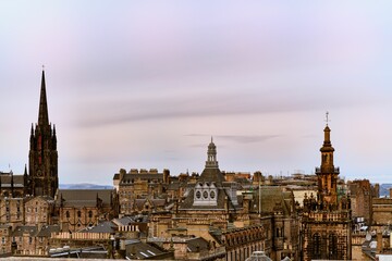 Fototapeta premium View of Edinburgh's historic skyline featuring iconic spires and architecture under a pastel sky.