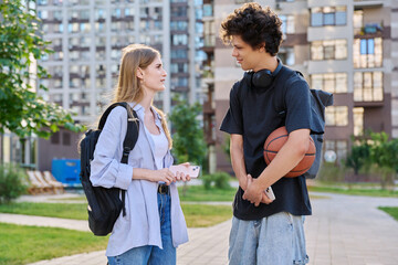 Young teenage guy and girl talking, walking together, urban background