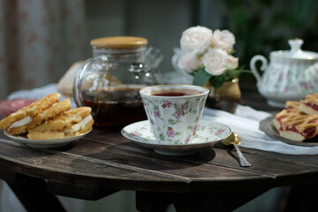 Tea party, morning breakfast. Cup of tea and fresh pastries on kitchen table. 