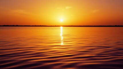Obraz premium A glowing sunset paints the sky orange and reflects over calm waters, creating a serene and picturesque end of the day.