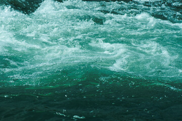 Blue water with ripples on the surface. Defocus blurred transparent blue colored clear calm water surface texture with splashes and bubbles. Water waves with shining pattern texture background.