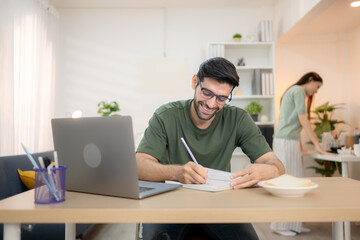 Fototapeta premium Portrait of a young freelancer smiling while working online via laptop at home with his girlfriend