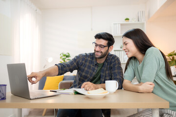 Portrait of a young freelancer smiling while working online via laptop at home with his girlfriend