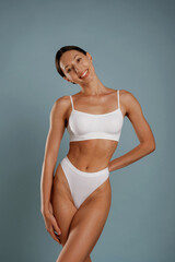 Fototapeta premium Fitness model is in white underwear. Young woman is in the studio against background