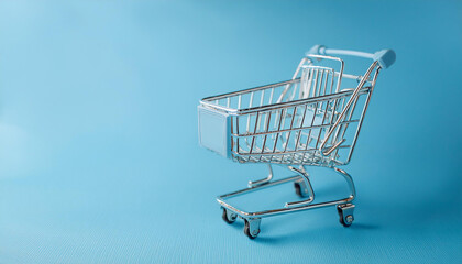 Mini supermarket cart on blue background. Online shopping, business concept.