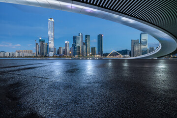 Asphalt road and bridge with modern city buildings at night
